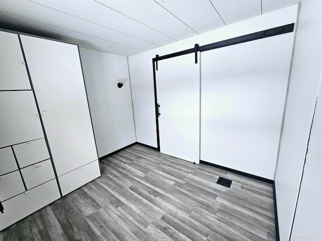 unfurnished bedroom featuring light wood-type flooring and a barn door