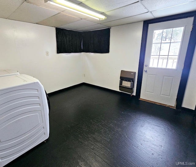 basement with a paneled ceiling and heating unit