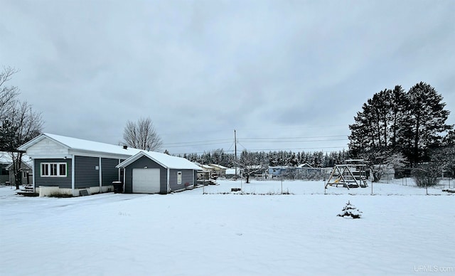 yard covered in snow featuring a garage and an outdoor structure