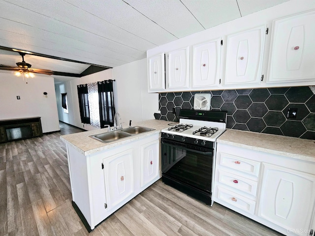 kitchen featuring light wood-type flooring, gas range gas stove, ceiling fan, sink, and white cabinets