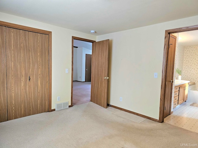 unfurnished bedroom with light carpet, connected bathroom, and a closet