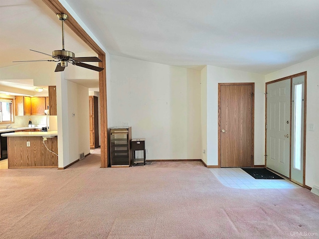 unfurnished living room featuring ceiling fan, lofted ceiling, and light carpet