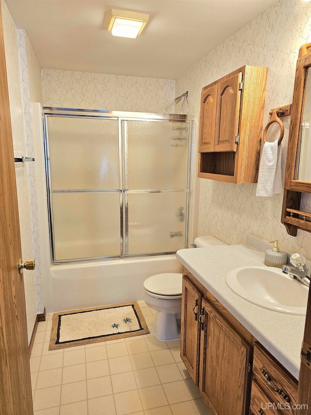 full bathroom with tile patterned floors, toilet, combined bath / shower with glass door, and vanity