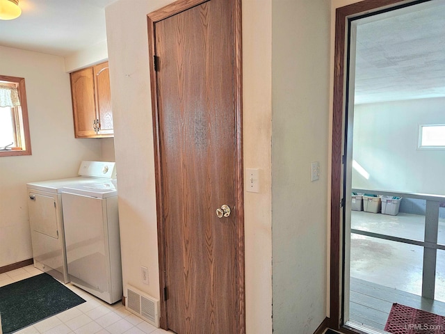 clothes washing area with cabinets, light tile patterned floors, separate washer and dryer, and a healthy amount of sunlight