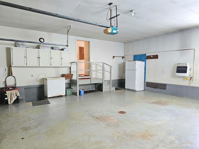 garage with heating unit, white fridge, and a garage door opener