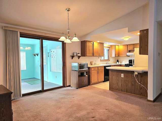 kitchen featuring light carpet, kitchen peninsula, black appliances, decorative light fixtures, and an inviting chandelier