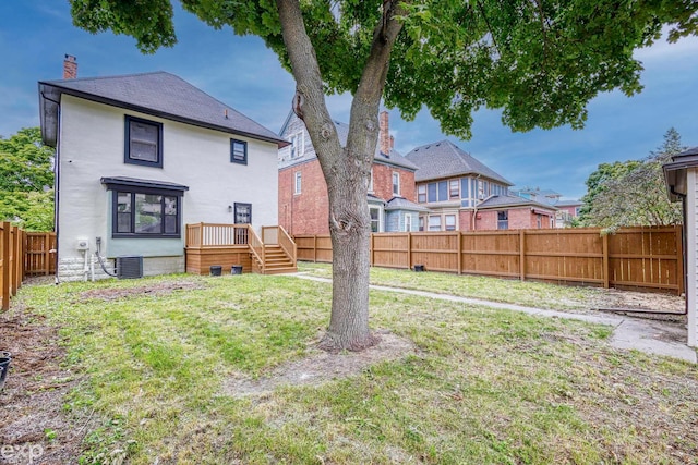 rear view of property with a deck, central AC unit, and a lawn