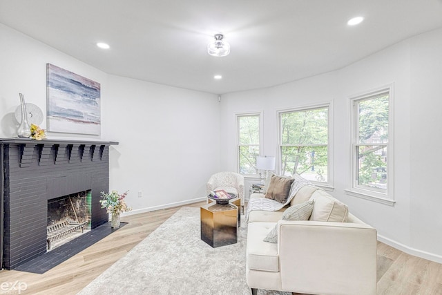 living room with a brick fireplace and light wood-type flooring