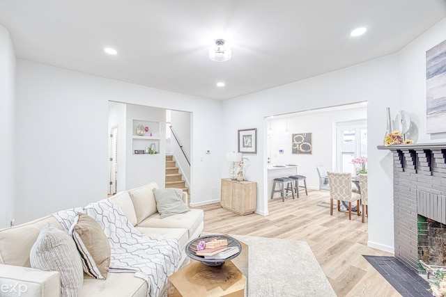 living room with light hardwood / wood-style flooring and a brick fireplace