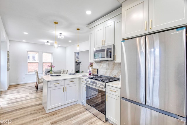 kitchen featuring decorative light fixtures, light wood-type flooring, kitchen peninsula, and stainless steel appliances