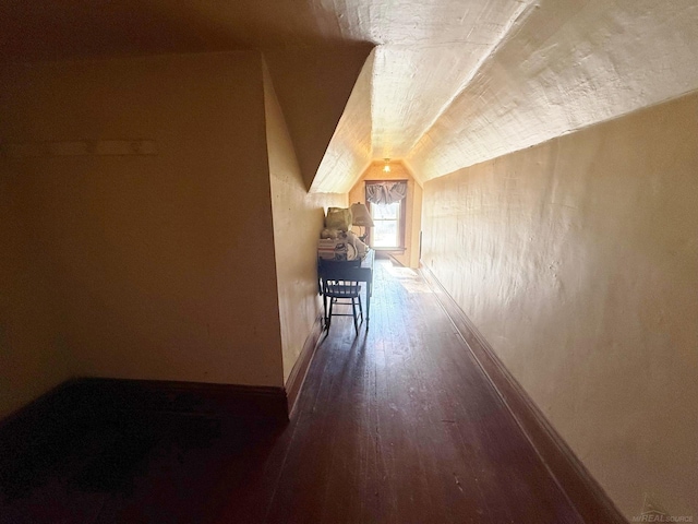 additional living space featuring dark wood-type flooring and vaulted ceiling