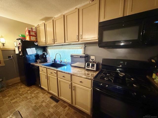 kitchen with cream cabinets, black appliances, sink, light stone countertops, and a textured ceiling