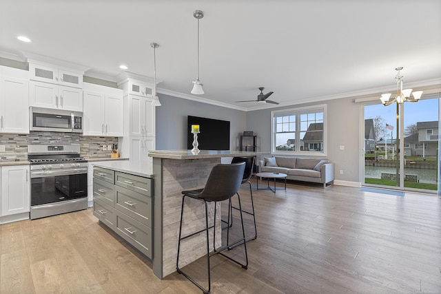 kitchen featuring a breakfast bar, stainless steel appliances, gray cabinets, white cabinetry, and hanging light fixtures