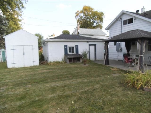 rear view of house featuring a storage shed, a patio area, a lawn, and an outdoor structure