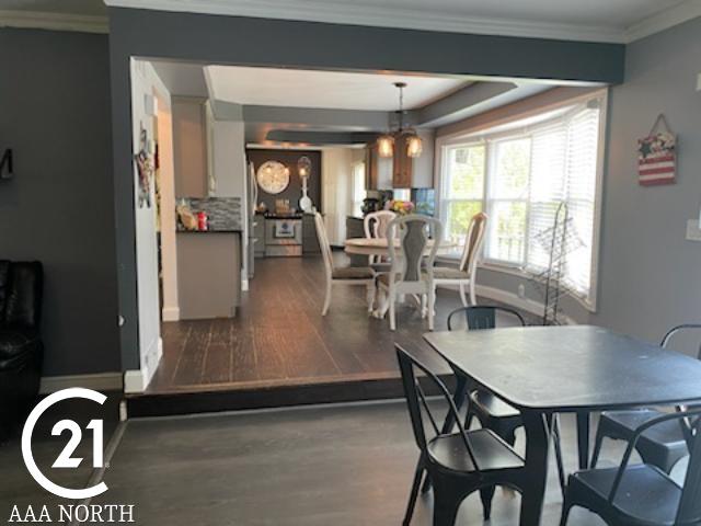 dining area featuring ornamental molding, dark wood-type flooring, and a notable chandelier