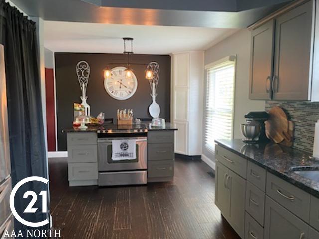 kitchen with stainless steel range with electric stovetop, dark stone counters, hanging light fixtures, gray cabinets, and dark hardwood / wood-style flooring