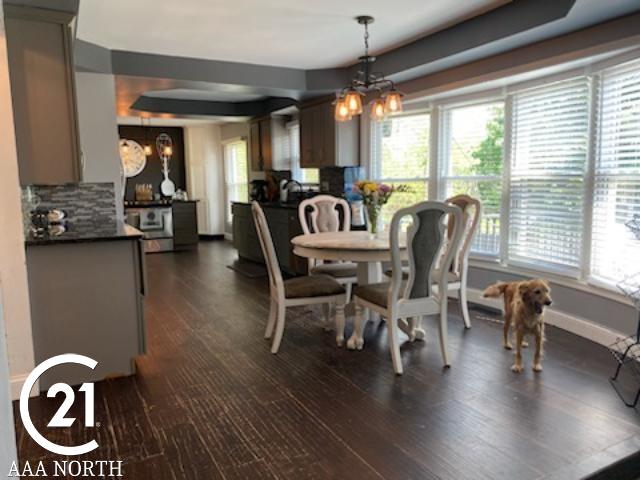 dining area featuring dark hardwood / wood-style floors, a tray ceiling, and a chandelier