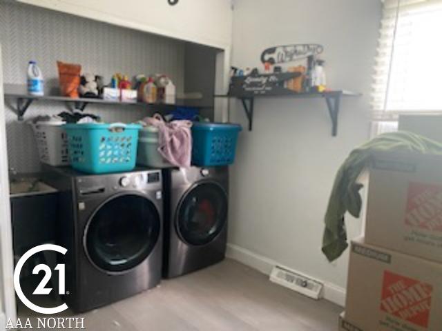 washroom with hardwood / wood-style flooring and separate washer and dryer