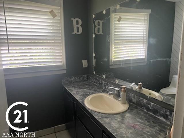 bathroom featuring tile patterned floors, a wealth of natural light, vanity, and toilet