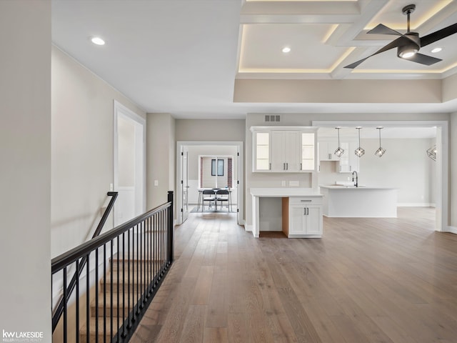 interior space featuring visible vents, a sink, an upstairs landing, wood finished floors, and baseboards