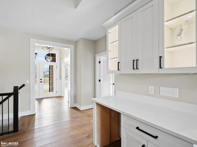 kitchen with light wood-type flooring, baseboards, white cabinetry, and light countertops