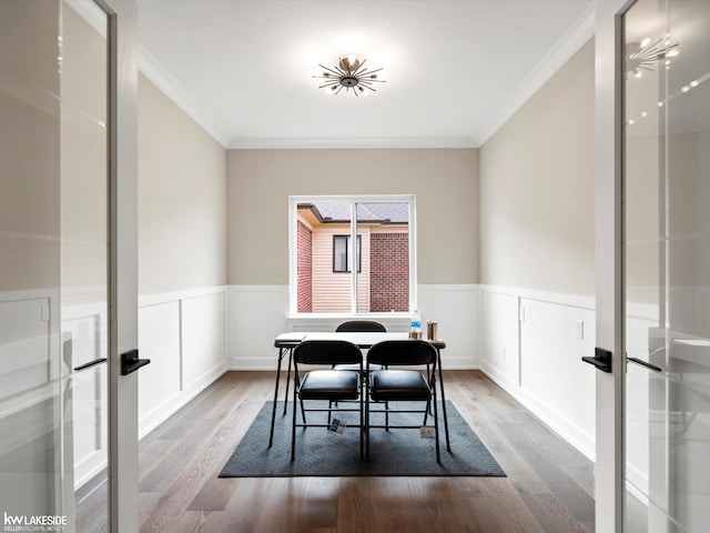 dining space featuring ornamental molding, a wainscoted wall, and wood finished floors