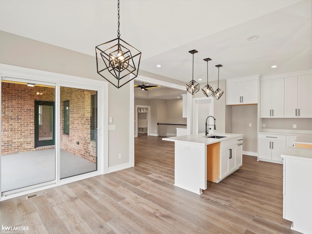 kitchen featuring light wood finished floors, light countertops, visible vents, open floor plan, and a sink