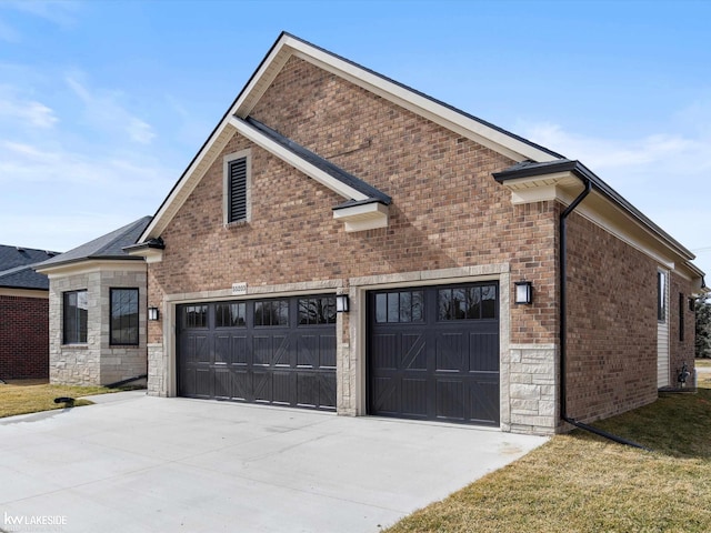 view of side of property featuring a garage, stone siding, brick siding, and driveway