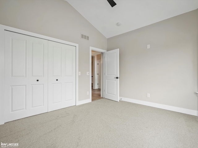 unfurnished bedroom featuring carpet floors, a closet, visible vents, high vaulted ceiling, and baseboards