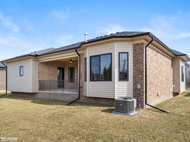 back of house with a ceiling fan, brick siding, a lawn, and central AC