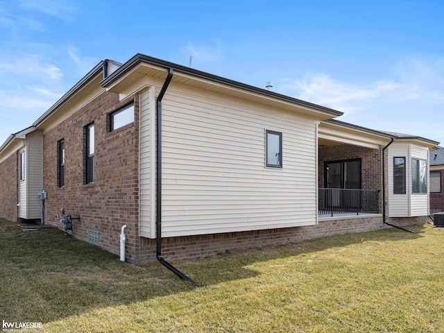 view of property exterior featuring crawl space, brick siding, and a lawn