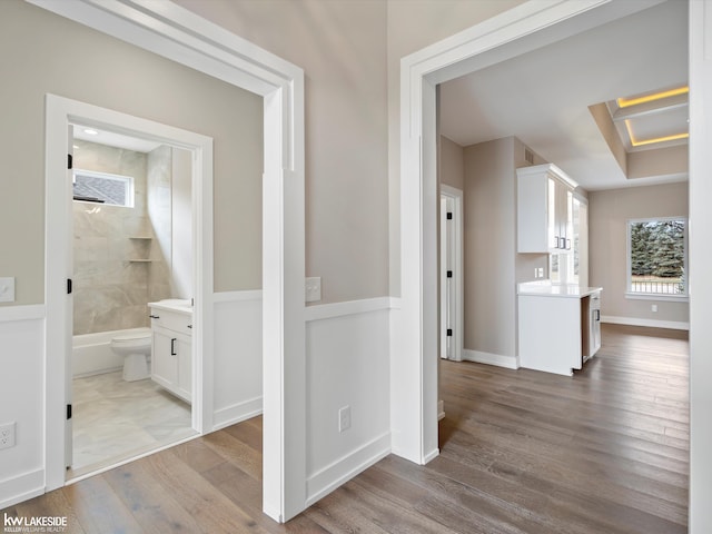 corridor with wood finished floors, attic access, and baseboards