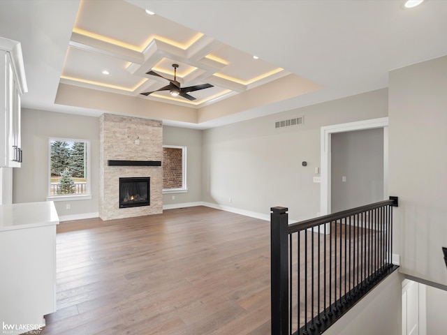 unfurnished living room featuring a fireplace, visible vents, wood finished floors, coffered ceiling, and baseboards