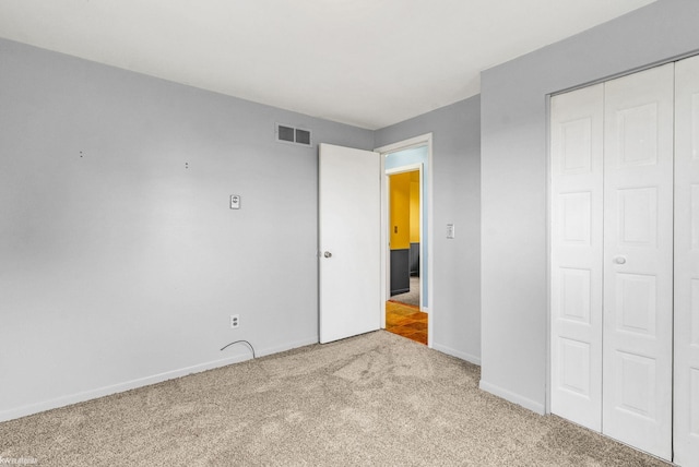 unfurnished bedroom featuring light colored carpet and a closet