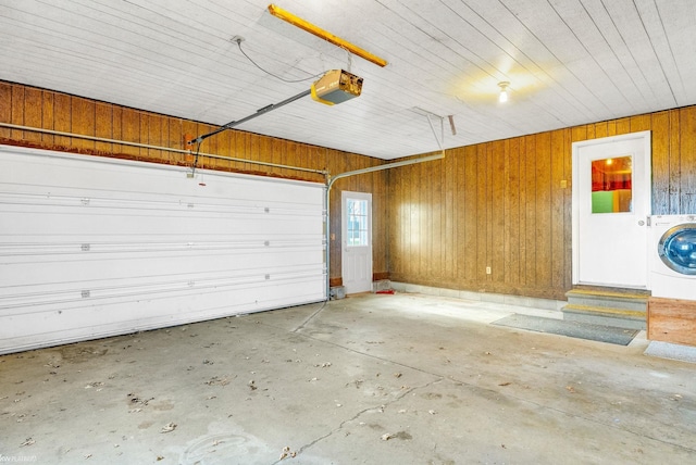 garage featuring washer / clothes dryer, a garage door opener, and wood walls