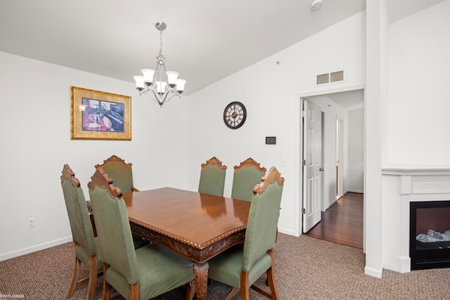 carpeted dining space with vaulted ceiling and a notable chandelier