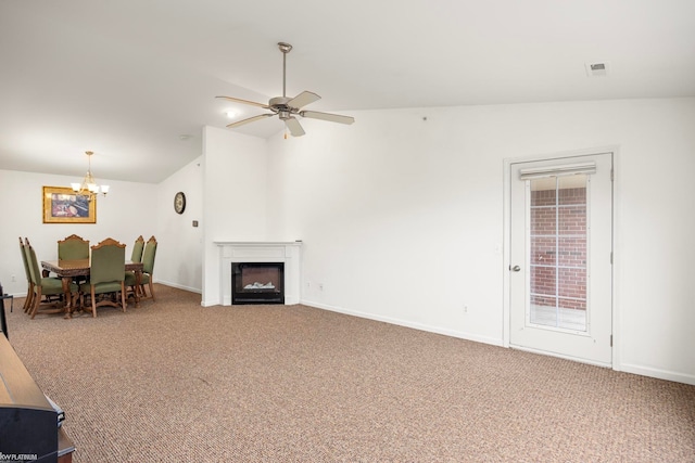 carpeted living room featuring vaulted ceiling and ceiling fan with notable chandelier