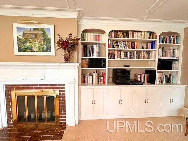 interior space featuring crown molding, carpet floors, and a brick fireplace