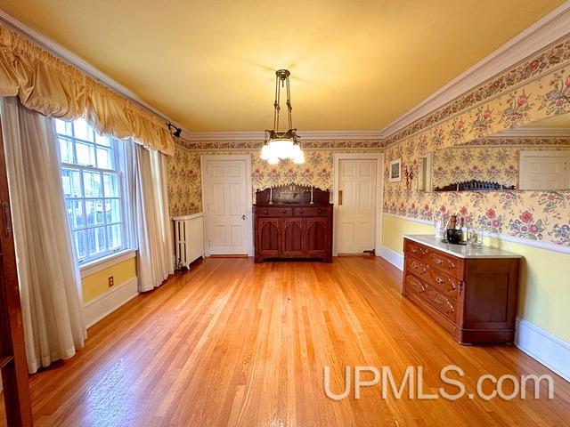 unfurnished dining area featuring radiator heating unit, light hardwood / wood-style flooring, and ornamental molding