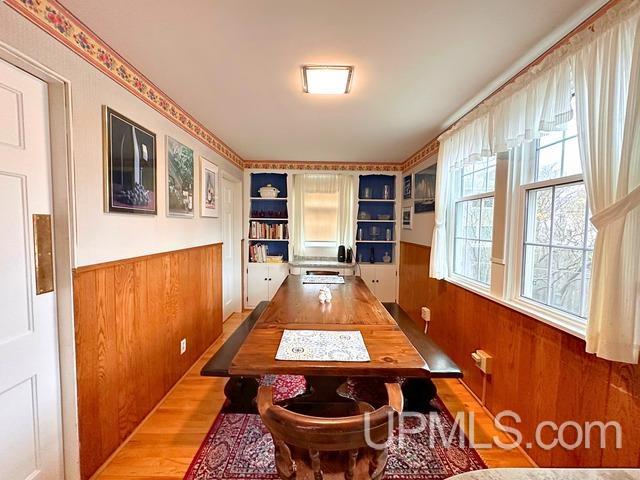 dining area featuring light wood-type flooring and wood walls