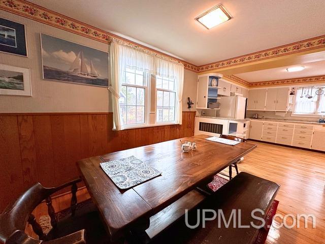 dining area featuring light wood-type flooring and wood walls