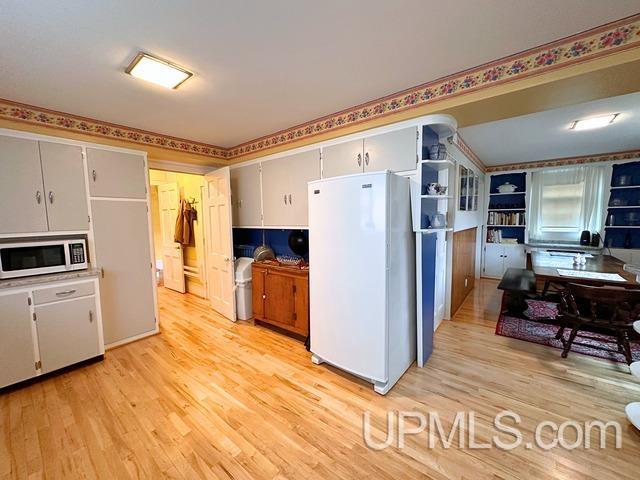 kitchen with white appliances and light hardwood / wood-style flooring