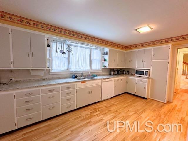 kitchen with light hardwood / wood-style floors, white appliances, sink, and white cabinetry