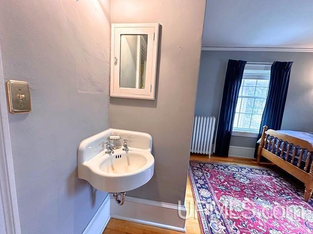 bathroom with radiator heating unit, crown molding, and hardwood / wood-style floors