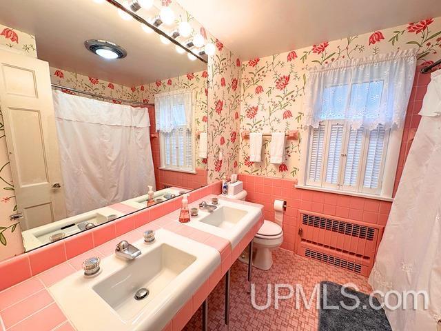 bathroom featuring radiator, tile walls, and toilet