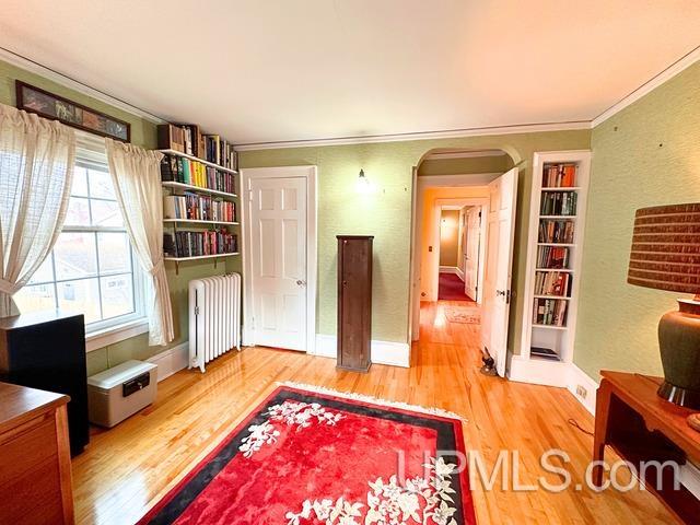 interior space featuring hardwood / wood-style floors, radiator heating unit, and crown molding