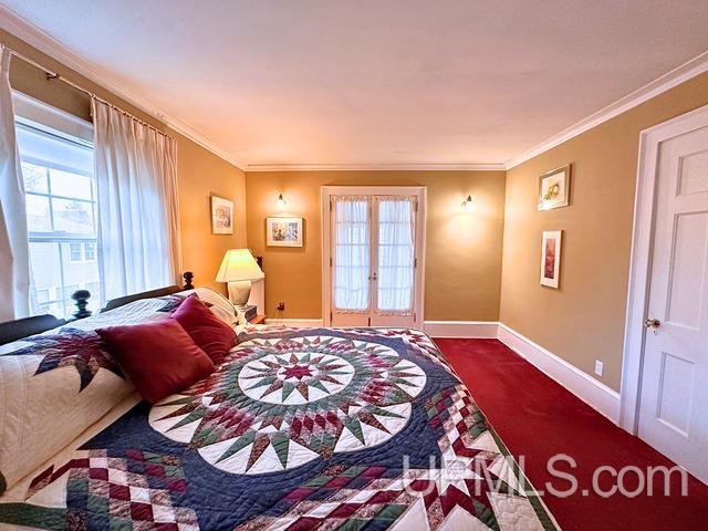 carpeted bedroom featuring crown molding and french doors