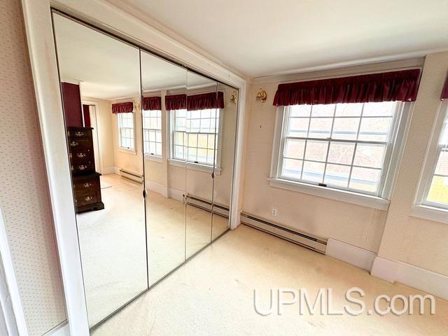 unfurnished bedroom with a closet and a baseboard heating unit