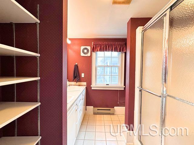 bathroom featuring a shower with door, tile patterned flooring, vanity, and a baseboard radiator