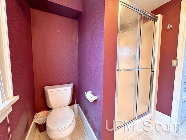 bathroom featuring tile patterned floors, toilet, and walk in shower